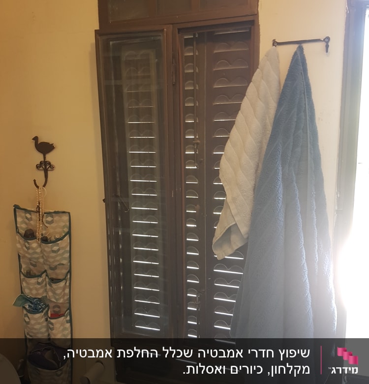 חלון עם תריסים, מגבות תלויות על מתלה